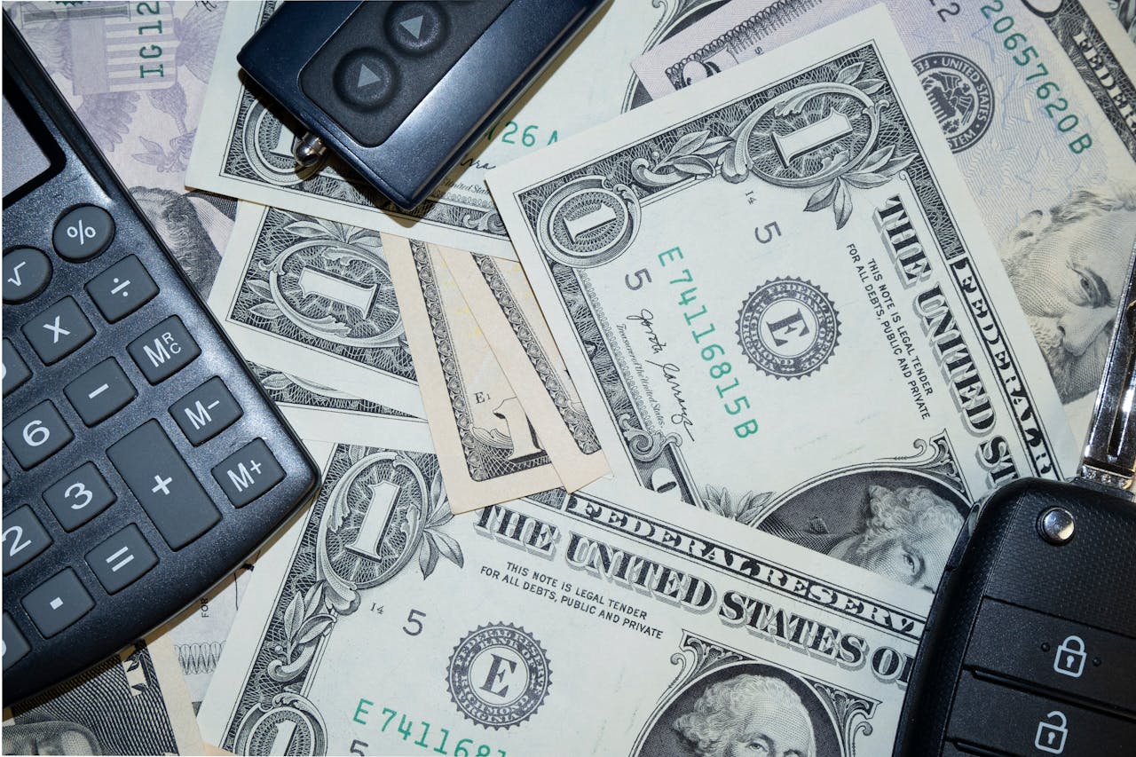 The Art of Drawing Readers In: Your attractive post title goes here An arrangement of US dollar bills, car keys, and a calculator representing finance and investment concepts.